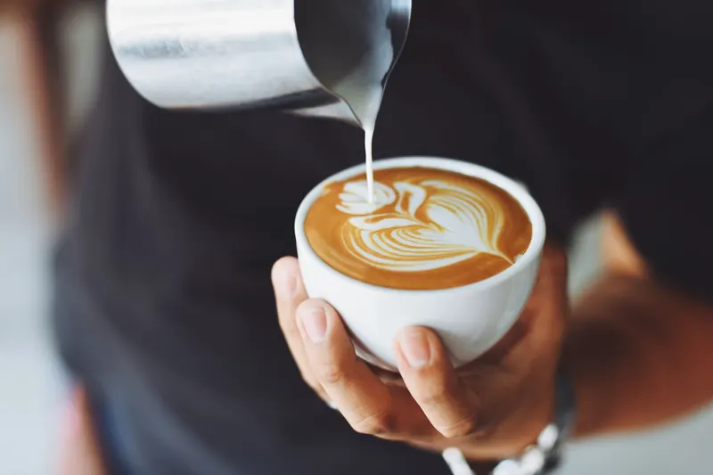 Una persona vierte leche en una taza de café