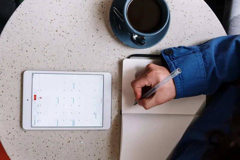 Una persona consulta un calendario junto a un cuaderno
