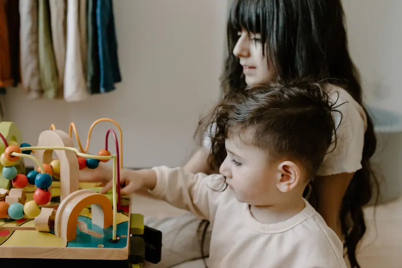 Dos niños juegan con juguetes de madera en una mesa