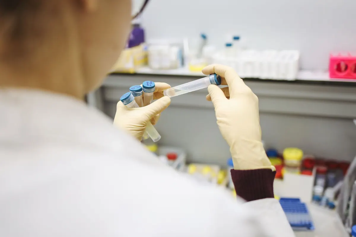 Manos con guantes sujetan tubos en un laboratorio
