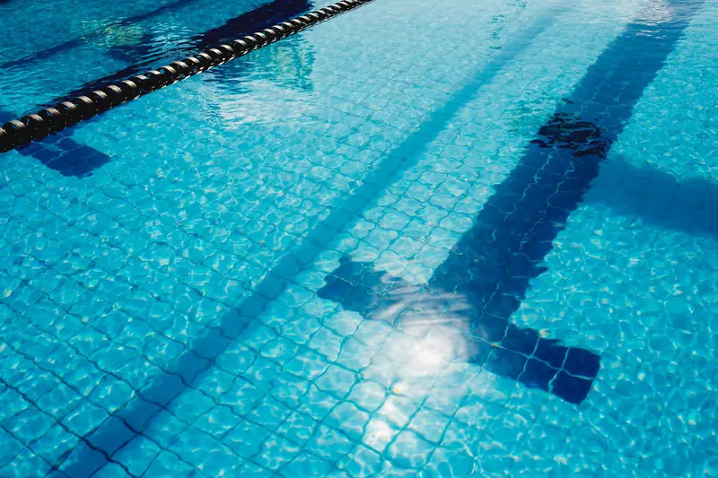 Agua azul de una piscina con una separación entre calles de natación