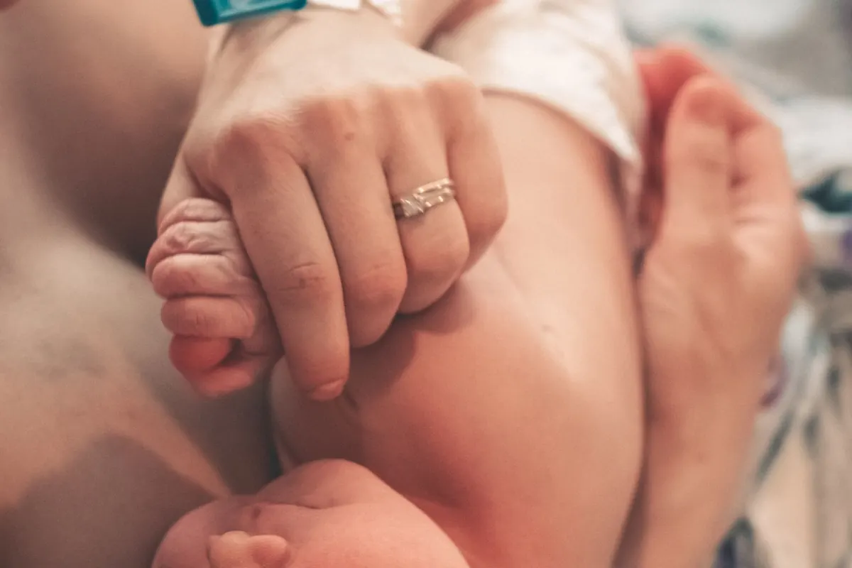 Un recién nacido agarra un dedo de su madre
