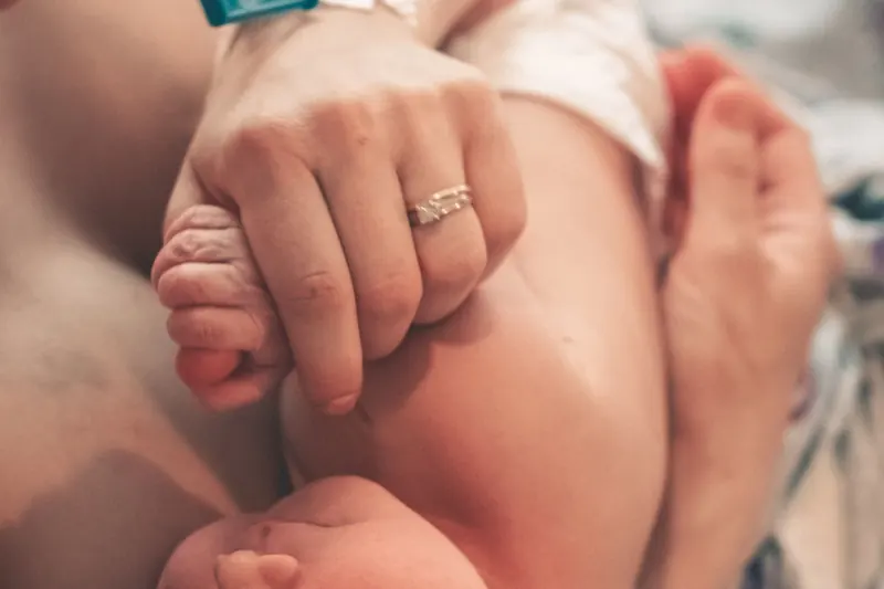 Un recién nacido agarra un dedo de su madre